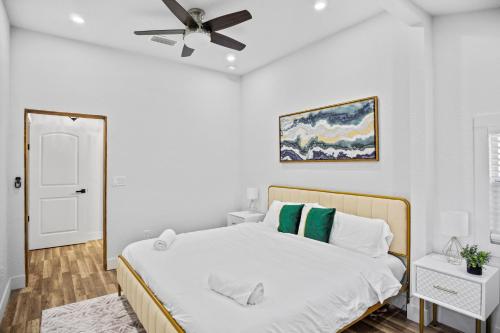 Chic and cozy private getaway! في تامبا: غرفة نوم بيضاء مع سرير ومروحة سقف