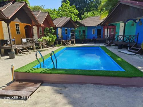 a swimming pool with grass in front of houses at Bee Chalet Perhentian Island in Perhentian Island