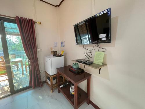 a room with a television on the wall and a table at เชียงคานพาราไดร์รีสอร์ท&มีตติ้ง in Ban Na Bon (1)