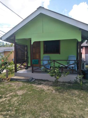 a small green house with two chairs on the porch at CEMPAKA CHALETS TIOMAN in Kampong Juara