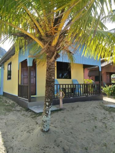 a palm tree in front of a house at CEMPAKA CHALETS TIOMAN in Kampong Juara