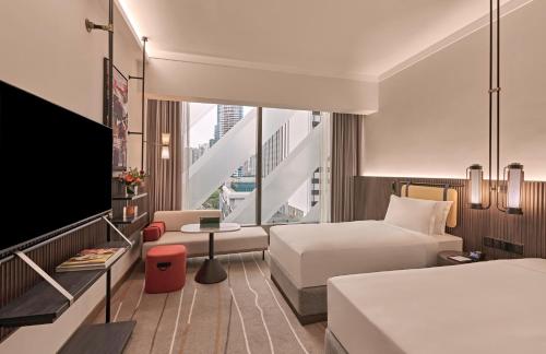 a hotel room with two beds and a flat screen tv at Pullman Singapore Orchard in Singapore