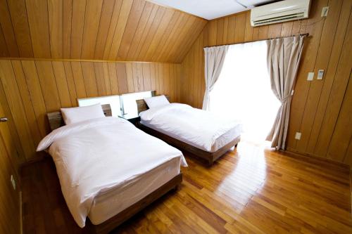Zimmer mit 2 Betten und einem Fenster in einem Zimmer in der Unterkunft 川平ハウス in Onna