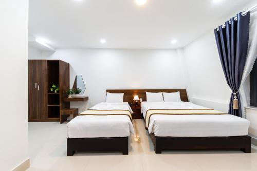 two beds in a room with white walls at Đà Lạt Cao Nguyên Hotel in Da Lat