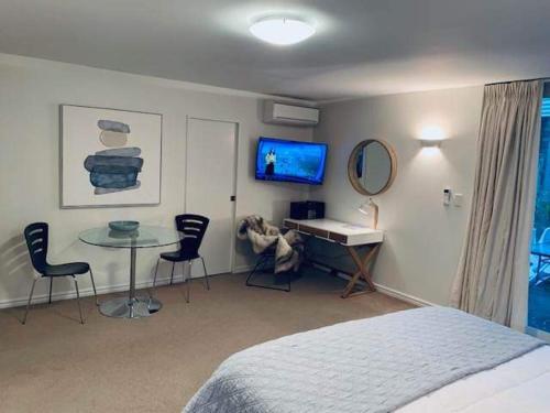 een slaapkamer met een bed, een bureau en een tafel bij Luxury Beach Guest House in Papamoa