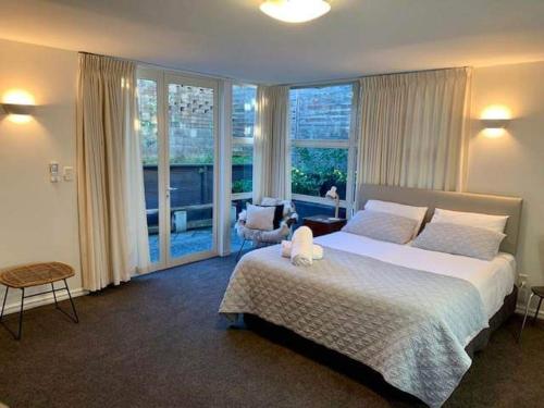 a bedroom with a large bed and a large window at Luxury Beach Guest House in Papamoa