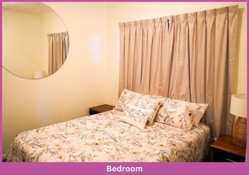 a bedroom with a bed with pillows and a mirror at Strand Park Unit - U1 Ground floor in Townsville