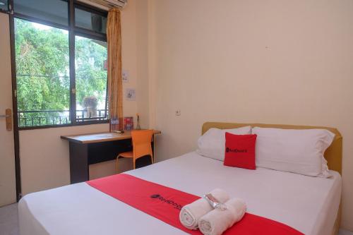 a bedroom with a bed with two towels on it at RedDoorz @ Jalan Pramuka Manado in Manado