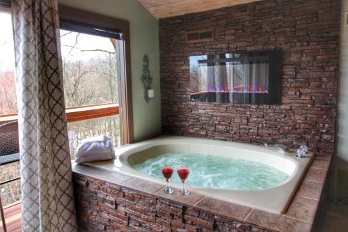 a jacuzzi tub with two wine glasses in it at Paradise Vista, Amazing Mtn Views, Hot Tub, 560 FREE tickets each paid day!!! in Gatlinburg