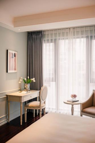 a hotel room with a desk and a window at Le Jardin Hotel Haute Couture in Hanoi