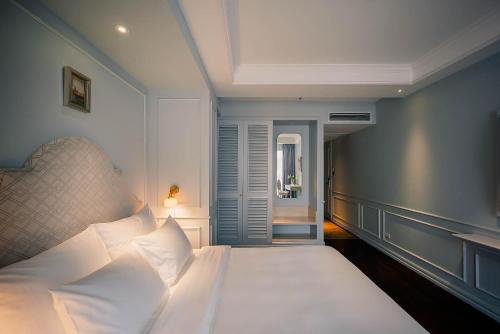 a bedroom with a bed with white pillows at Le Jardin Hotel Haute Couture in Hanoi