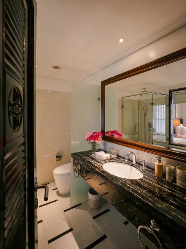 a bathroom with a sink and a mirror and a toilet at Le Jardin Hotel Haute Couture in Hanoi