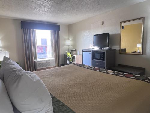 a hotel room with a bed and a television at Super 8 by Wyndham Ft Stockton in Fort Stockton