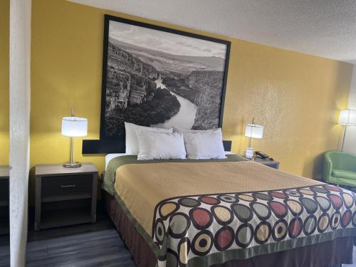 a hotel room with a bed and a painting on the wall at Super 8 by Wyndham Ft Stockton in Fort Stockton