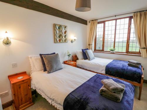 a bedroom with two beds and a window at Condicote Cottage in Weston on Avon