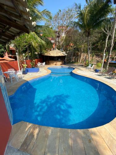 uma grande piscina azul com um deque de madeira em Hotel Cave do Sol em São Pedro da Aldeia