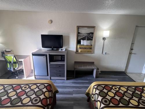 a hotel room with two beds and a flat screen tv at Super 8 by Wyndham Ft Stockton in Fort Stockton