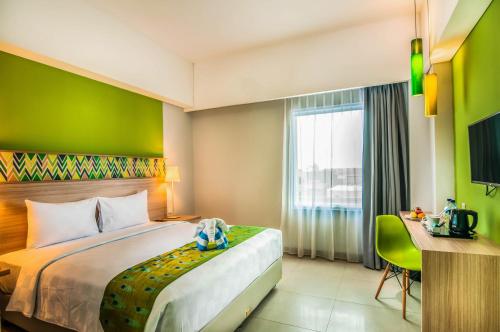 a hotel room with a bed and a desk and a window at KHAS Makassar Hotel in Makassar