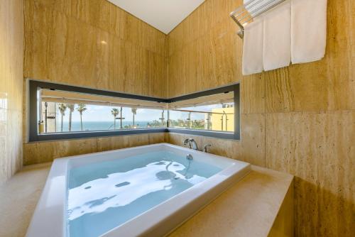 STANFORD Hotel & Resort Jeju في جيجو: حوض استحمام كبير في غرفة مع نافذة