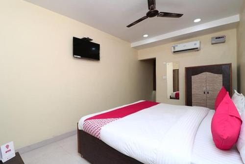 een slaapkamer met een bed met roze kussens en een televisie bij RNB Beach Stay in Anjuna