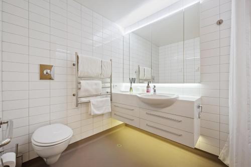 a white bathroom with a sink and a toilet at Bay Suites - 328 Oriental Parade Wellington in Wellington