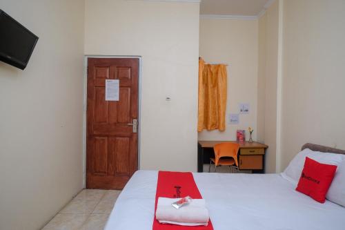 a room with two beds and a door and a desk at RedDoorz near Jalan Wolter Monginsidi Manado in Manado