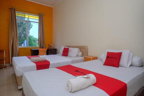 a bedroom with two beds with red and white pillows at RedDoorz near Jalan Wolter Monginsidi Manado in Manado