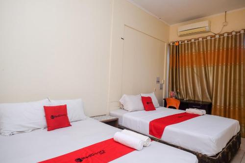 two beds in a room with red and white pillows at RedDoorz near Jalan Wolter Monginsidi Manado in Manado