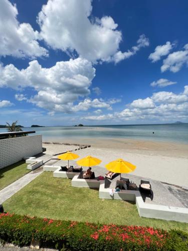 a group of people sitting under umbrellas on the beach at LANTA PURA beach resort-SHA extra plus in Ko Lanta