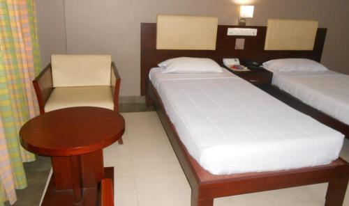 Zimmer mit 2 Betten, einem Tisch und einem Schreibtisch in der Unterkunft Hotel Nayana in Vāzhākulam