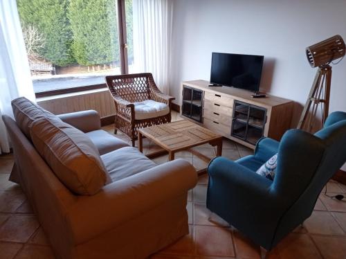 uma sala de estar com um sofá e cadeiras e uma televisão em Casa con encanto en La Hayuela, situada a 5 min de Comillas em Udias