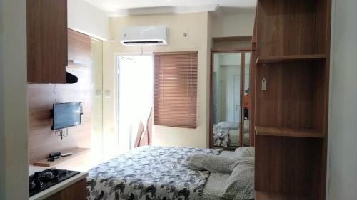 ein Schlafzimmer mit einem Bett und einem TV. in der Unterkunft Apartemen Green Pramuka City in Jakarta