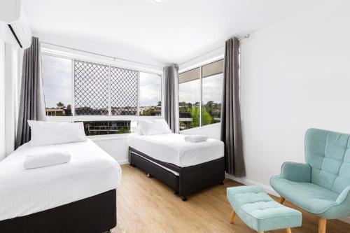 a bedroom with two beds and a chair and a window at ALEXANDRA BEACH RESORT-ALEX412 in Alexandra Headland