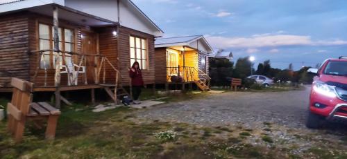 una cabaña de madera con un coche aparcado delante de él en Cabañas Campestres Las Rosas en Punta Arenas