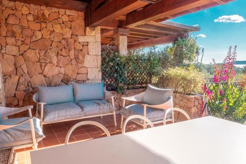 a patio with chairs and a stone wall at Villa Valentina 250m From The Beach - Happy Rentals in Puntaldia