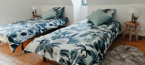 a bedroom with two beds with blue and white sheets at La cressonnière maison vue sur étang avec bain finlandais in La Rivière Saint Sauveur