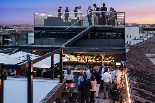a crowd of people standing around a bar on a roof at Golden Tulip Rome Piram in Rome