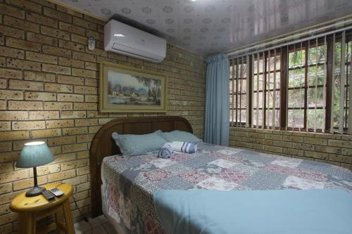 een slaapkamer met een bed en een bakstenen muur bij Xanadu Guest House in Sea Park