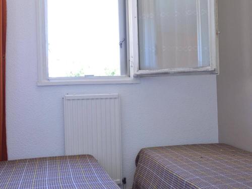 - 2 lits dans une chambre avec une fenêtre et un radiateur dans l'établissement Cap d'Agde: Studio cabine 4 pers, piscine, plage à 600m, parking - FR-1-249-6, au Cap d'Agde