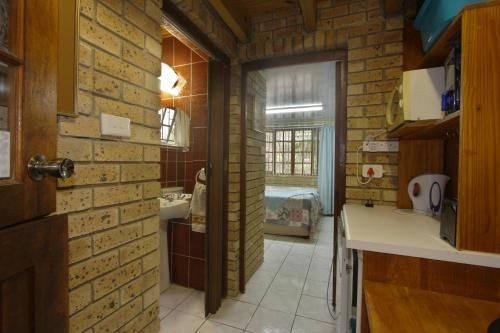 een keuken met een bakstenen muur en een kamer met een wastafel bij Xanadu Guest House in Sea Park