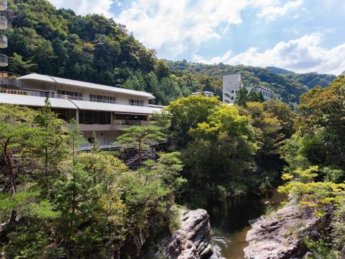 a building on a hill next to a river at Shin Kabakawa Kanko Hotel in Takamatsu