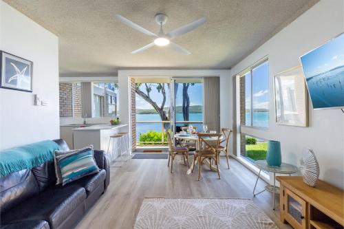 a living room with a couch and a table at Kooringal 6, 105 Soldiers Point Rd - waterfront unit in Soldiers Point