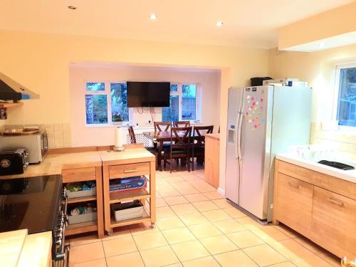 eine Küche mit einem weißen Kühlschrank und einem Tisch in der Unterkunft Specious 3bed property with parking & large garden in Aveley