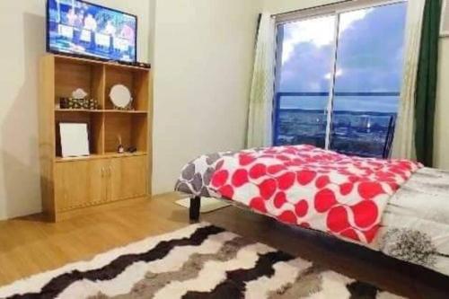 Un dormitorio con una cama y un televisor y una ventana. en CityView Condo with balcony-12, en Cagayan de Oro