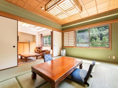a dining room with a wooden table and windows at Shin Kabakawa Kanko Hotel in Takamatsu