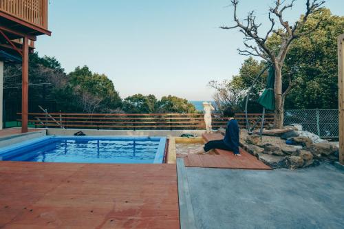 a person sitting on a deck next to a swimming pool at Diamond・Yu　Atami in Ajiro