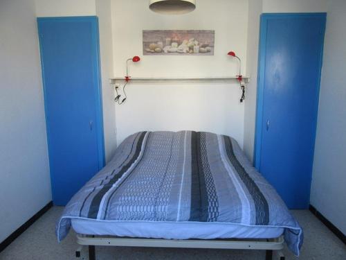 Cette chambre dispose de deux portes bleues et d'un lit. dans l'établissement Appartement climatisé avec grande terrasse, proche plages et équipé pour 5 personnes - FR-1-326-657, à Marseillan