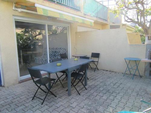 une table et des chaises bleues sur une terrasse dans l'établissement Appartement climatisé avec grande terrasse, proche plages et équipé pour 5 personnes - FR-1-326-657, à Marseillan