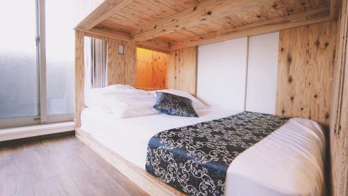 1 dormitorio con 1 cama en una habitación con paredes de madera en Poly Hostel Osaka, en Osaka