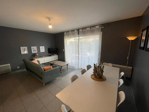 una sala de estar con una mesa y un sofá en Appartement en rez-de-jardin à 100m de la plage avec terrasse et parking - FR-1-413-107, en Capbreton